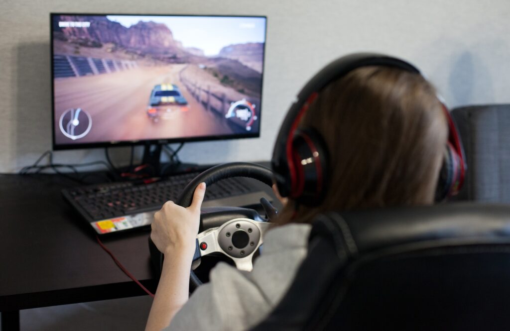young woman playing a video game driving, people using technology, gaming and playing computer games